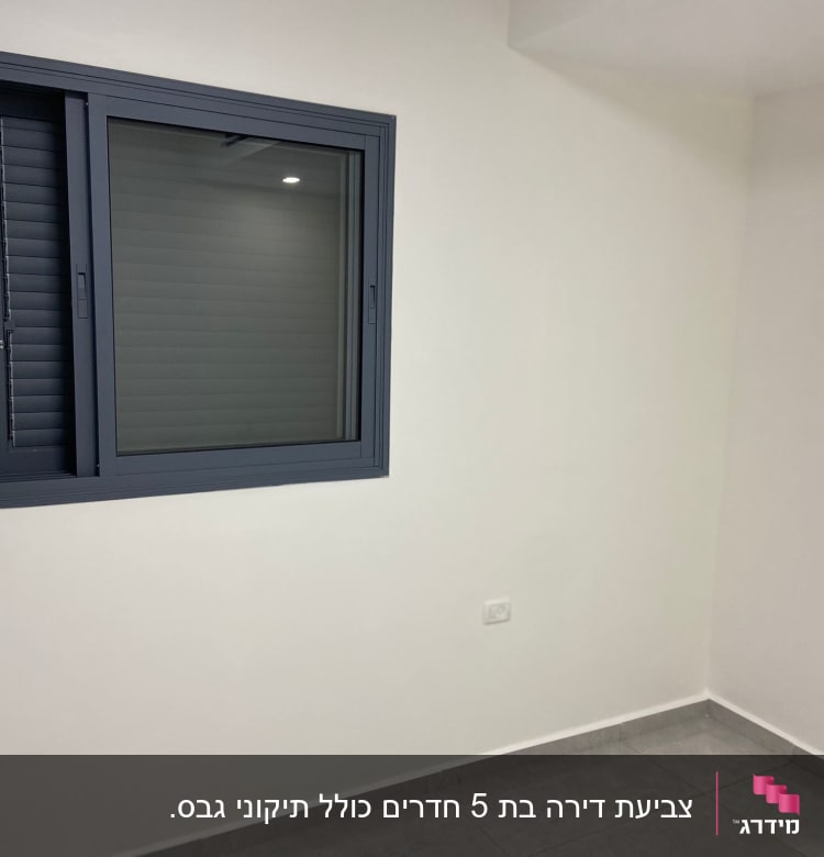 קיר צבוע בלבן עם חלון כהה